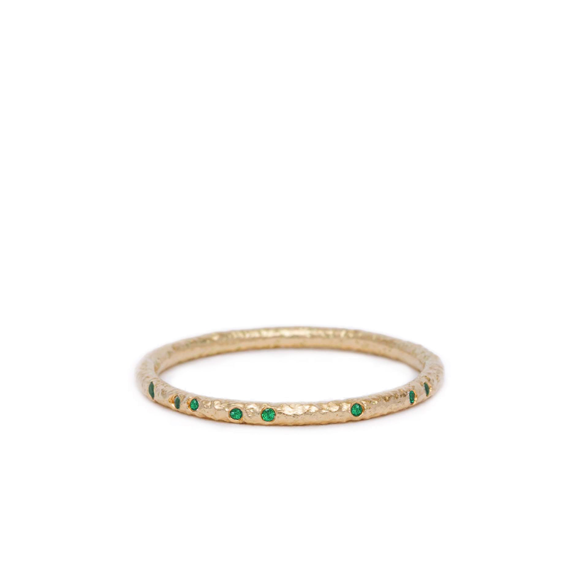 Gold ring with emerald gemstones on a white background