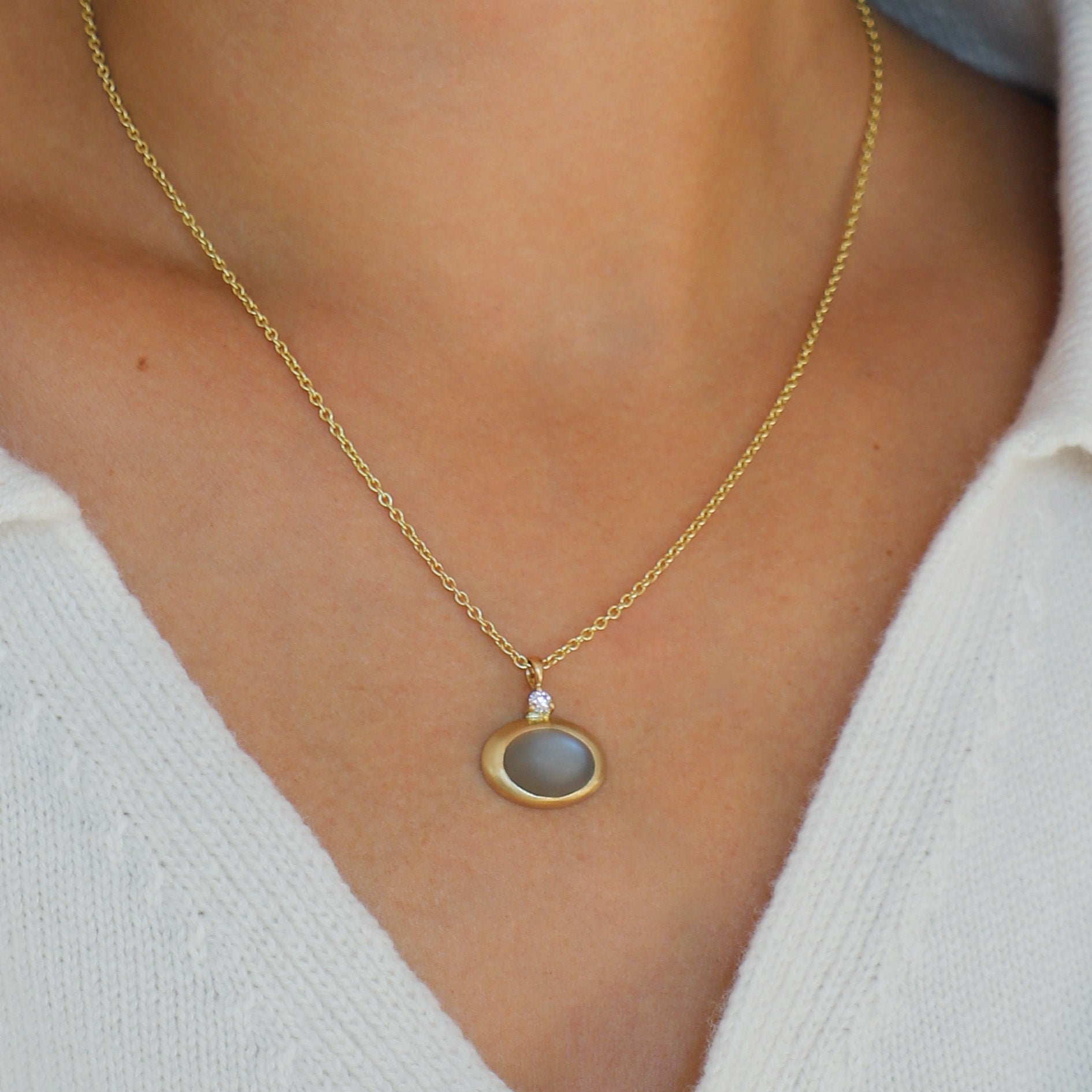 Gold necklace with a moonstone pendant worn by a person