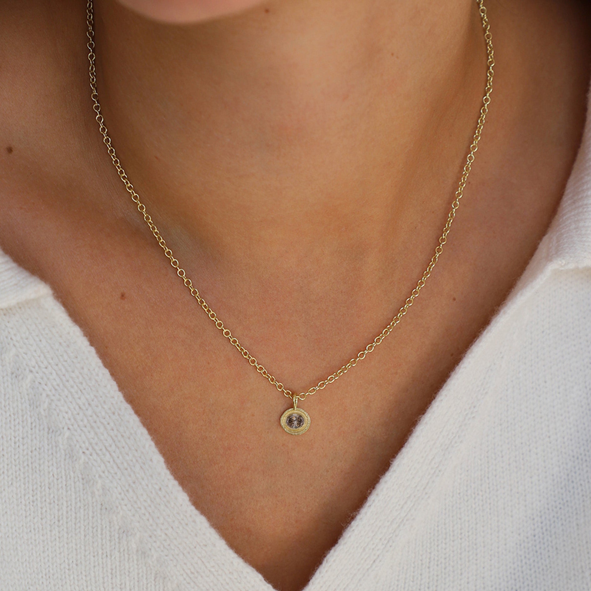 Gold necklace with a champagne diamond pendant on a person