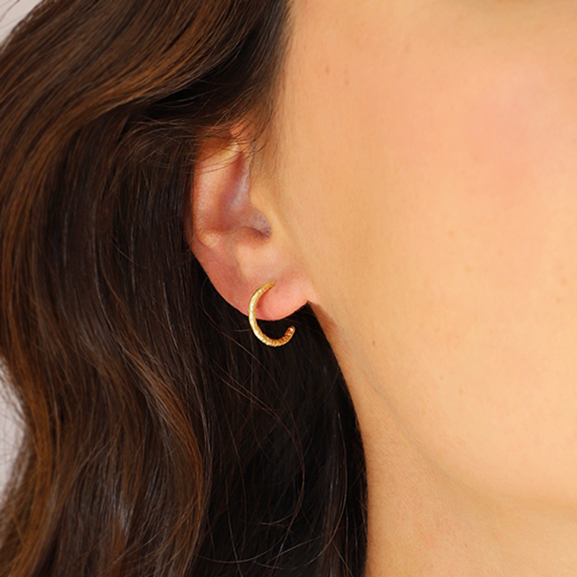 Close-up of a person wearing a gold hoop earring