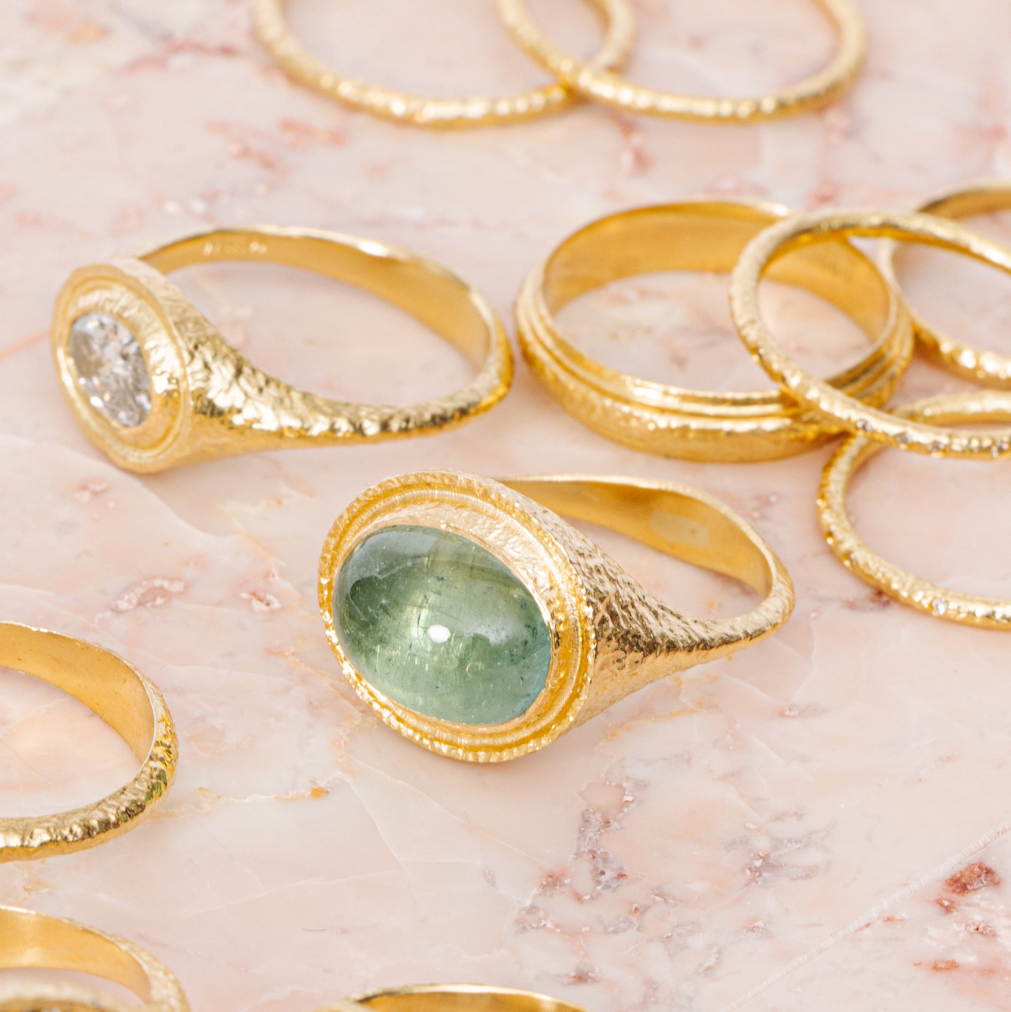 maya selway fine jewellery still life, scattering of textured 18ct yellow gold and diamond and tourmaline rings