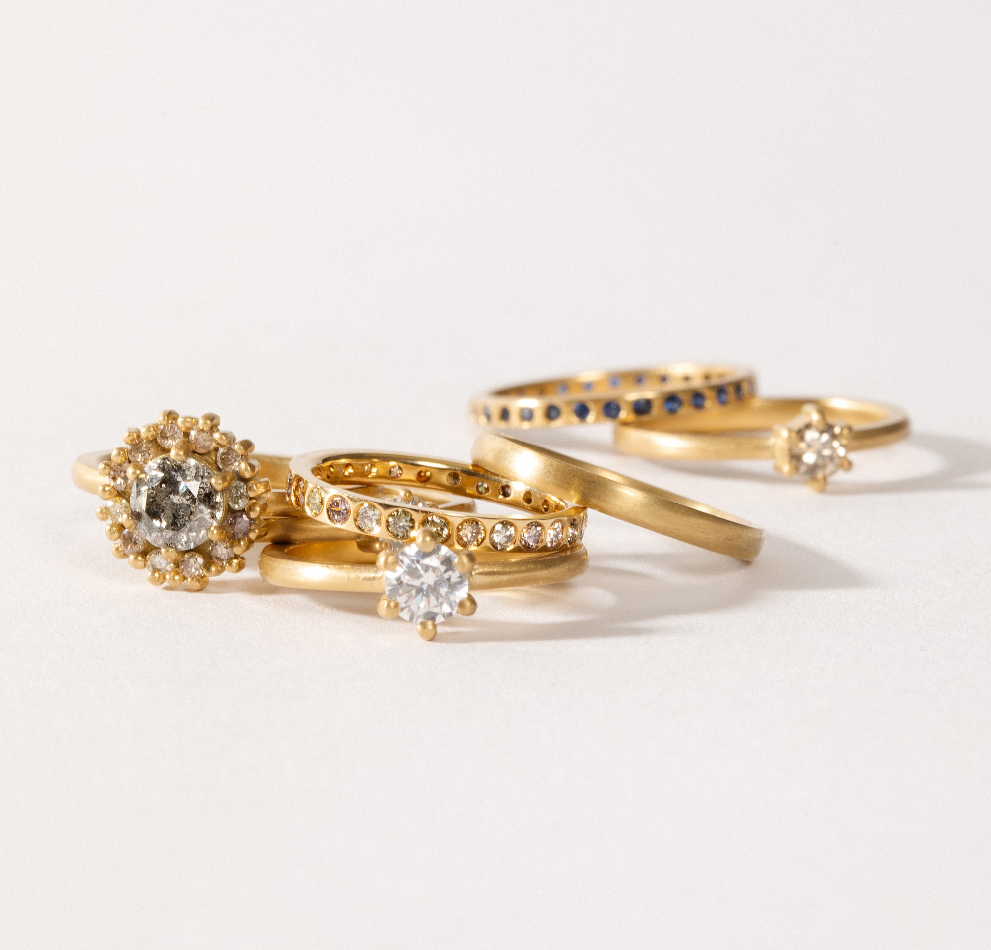 maya selway fine jewellery still life, scattering of textured and matte 18ct yellow gold and diamond rings
